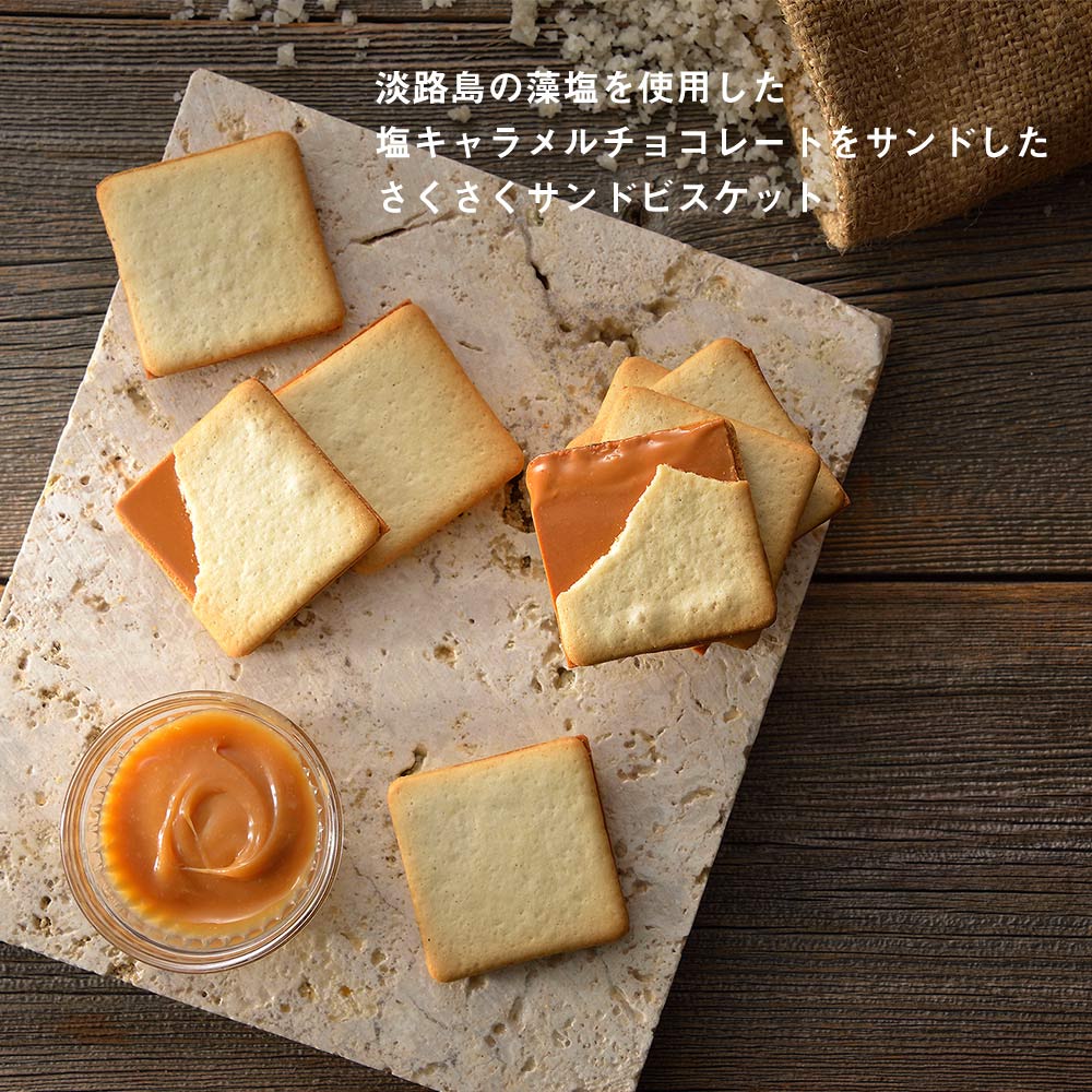 A wooden box with a green bird design on the lid. The bird has a small gift box in its mouth, and there is a yellow band with Japanese writing that says "arigato gozaimasu," which means "thank you very much." Inside the box, there are four individually wrapped salted caramel cookies.