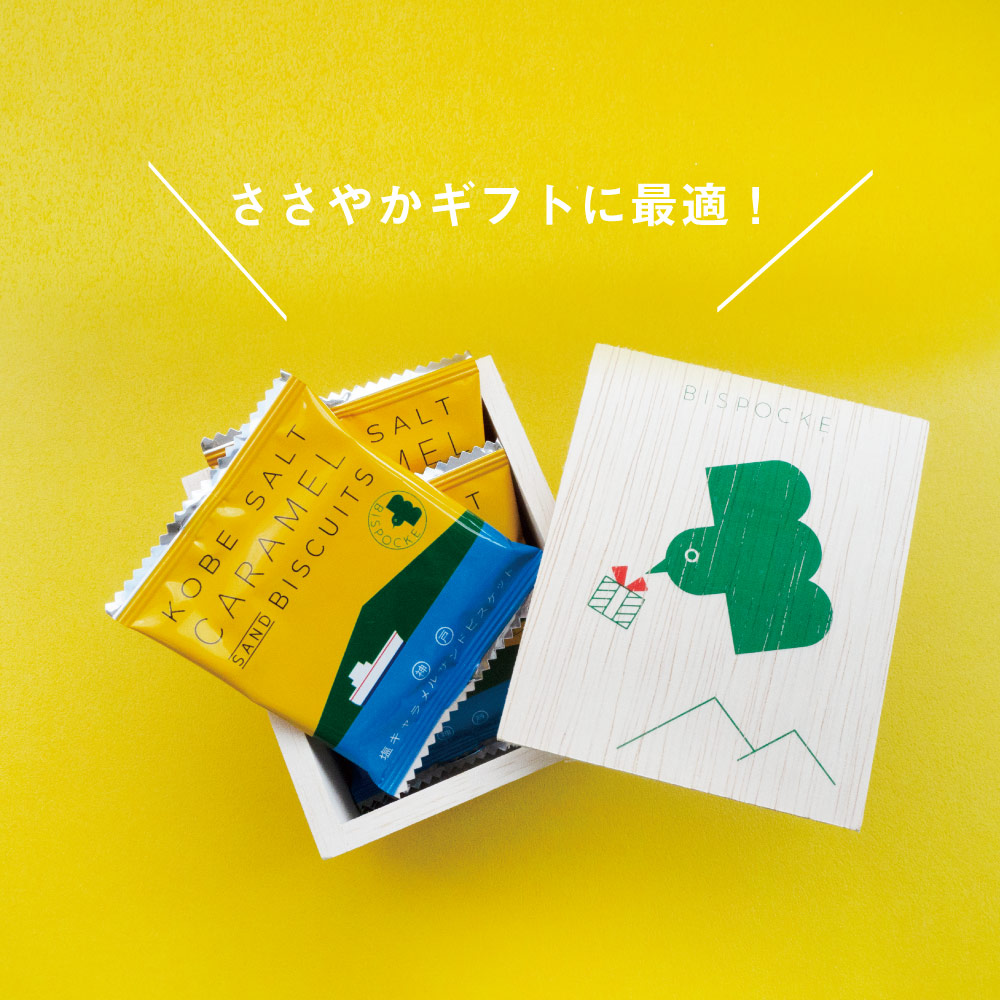 A wooden box with a green bird design on the lid. The bird has a small gift box in its mouth, and there is a yellow band with Japanese writing that says "arigato gozaimasu," which means "thank you very much." Inside the box, there are four individually wrapped caramel cookies.