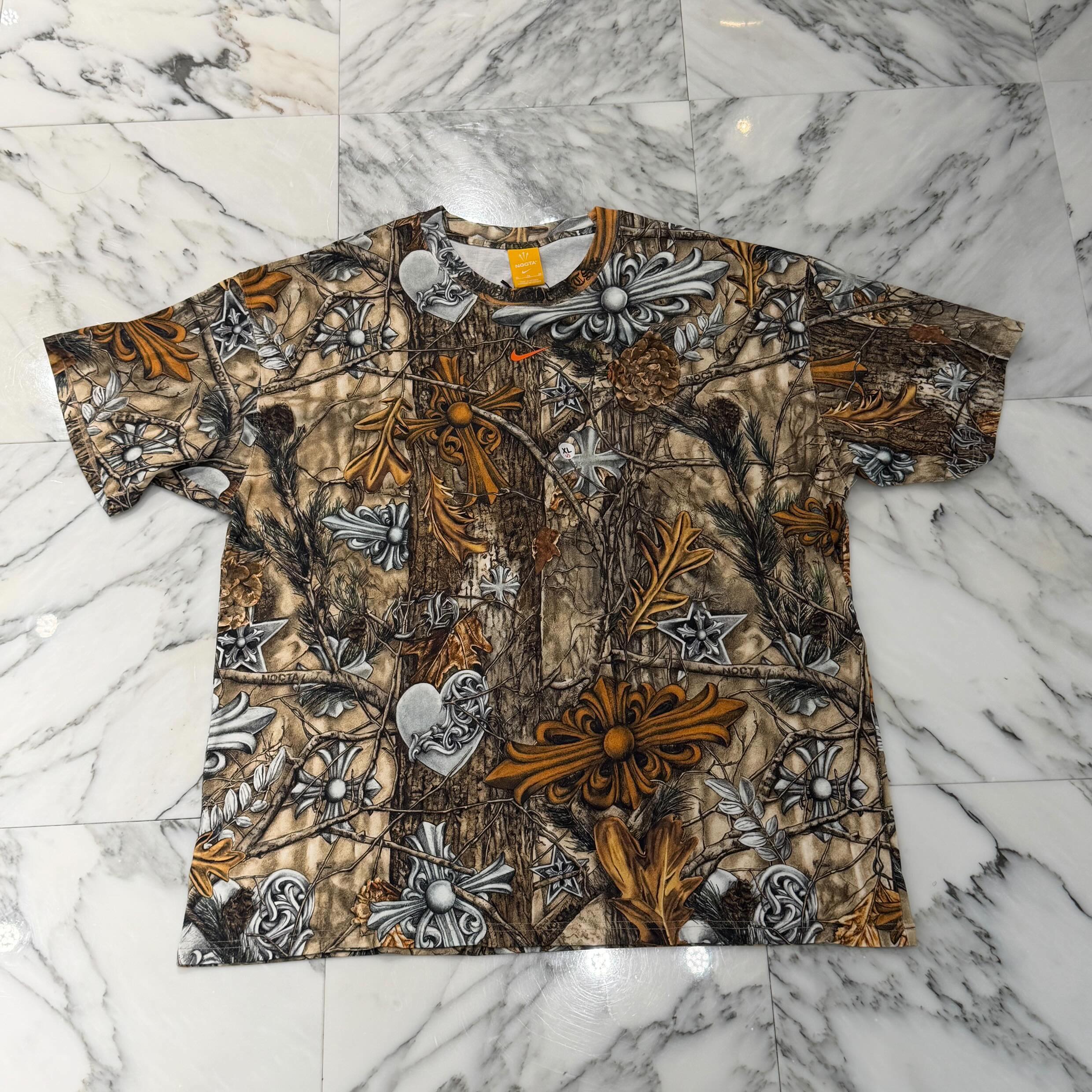 CHROME HEARTS × NIKE × Drake NOCTA 2026SS Camo Neck Logo Tee Size XL クロムハーツ×ナイキ×ドレイク ノクタ カモネックロゴ Tシャツ 半袖カットソー ラバーロゴ カモフラ フローラルクロス ホースシュー カモフラ×マルチカラー サイズXL 【260621】【新古品】|メメントスオンライン店